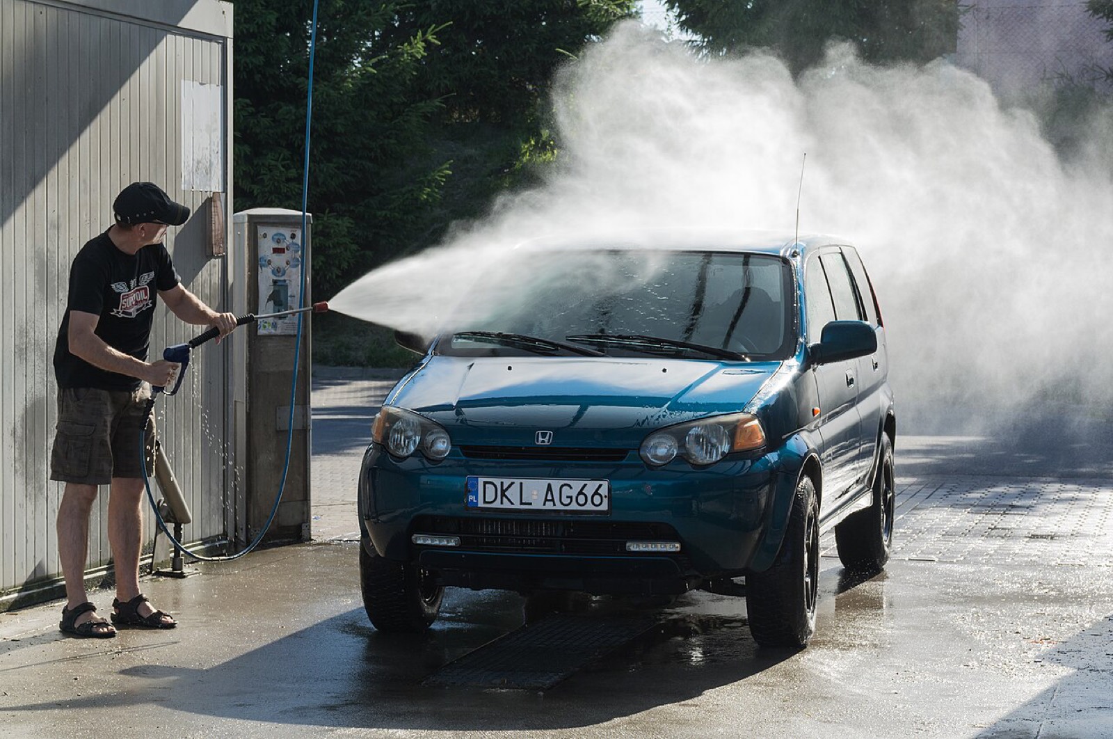 Attendant pressure-washing a car at a wash bay