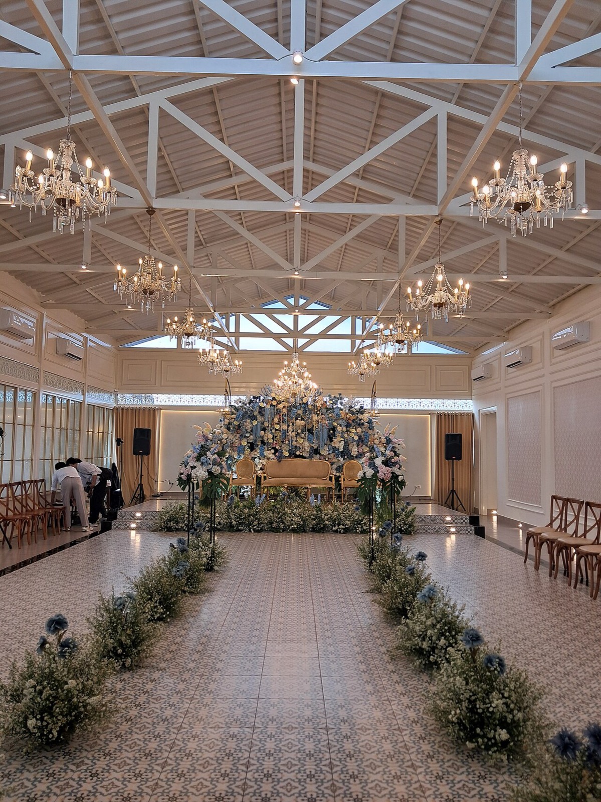 Wedding reception hall with chandeliers and a floral aisle
