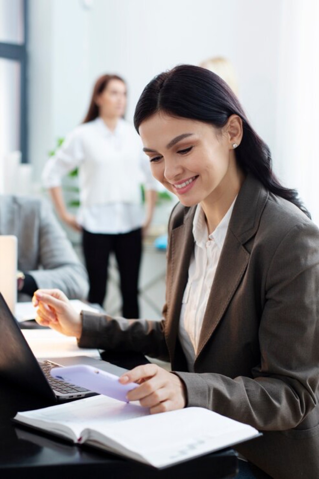 Woman reviewing notes on a laptop in an office